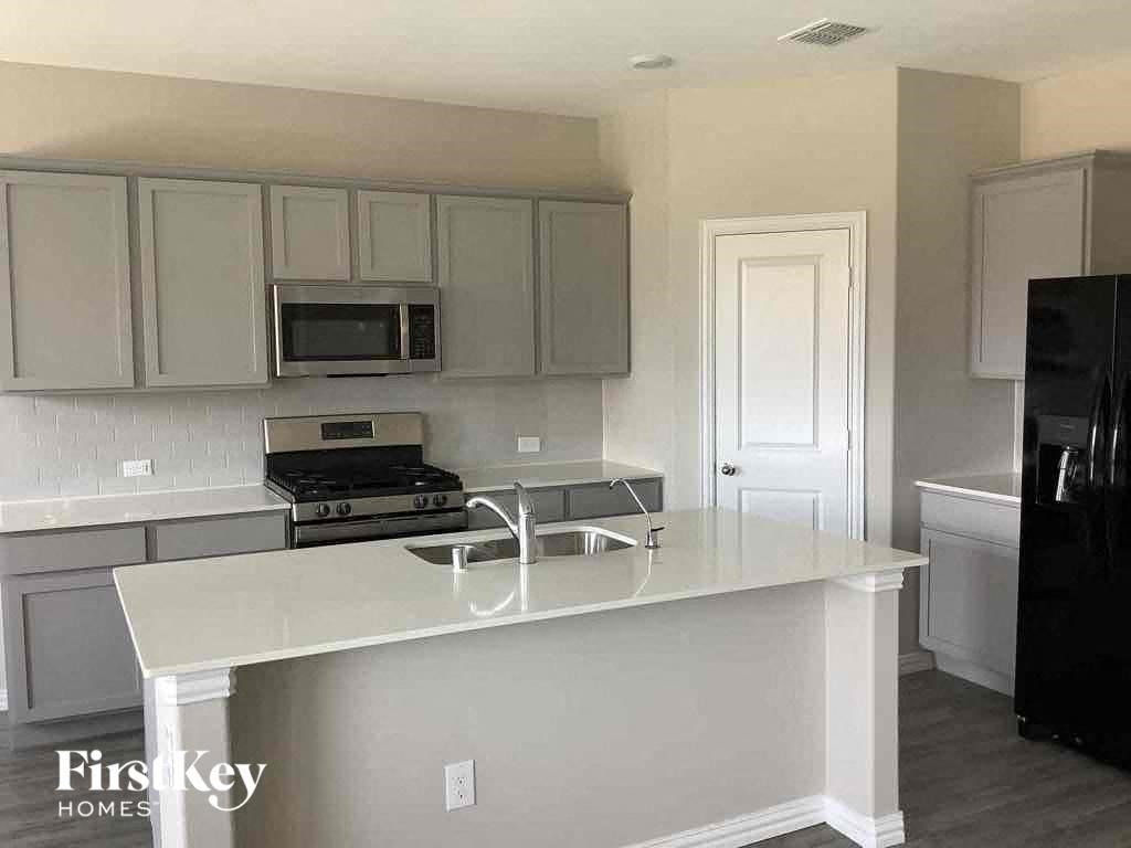 an empty kitchen with white cabinets and a counter top