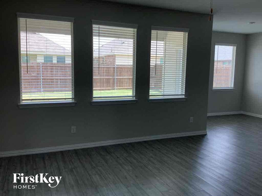 an empty living room with three windows and a wood floor