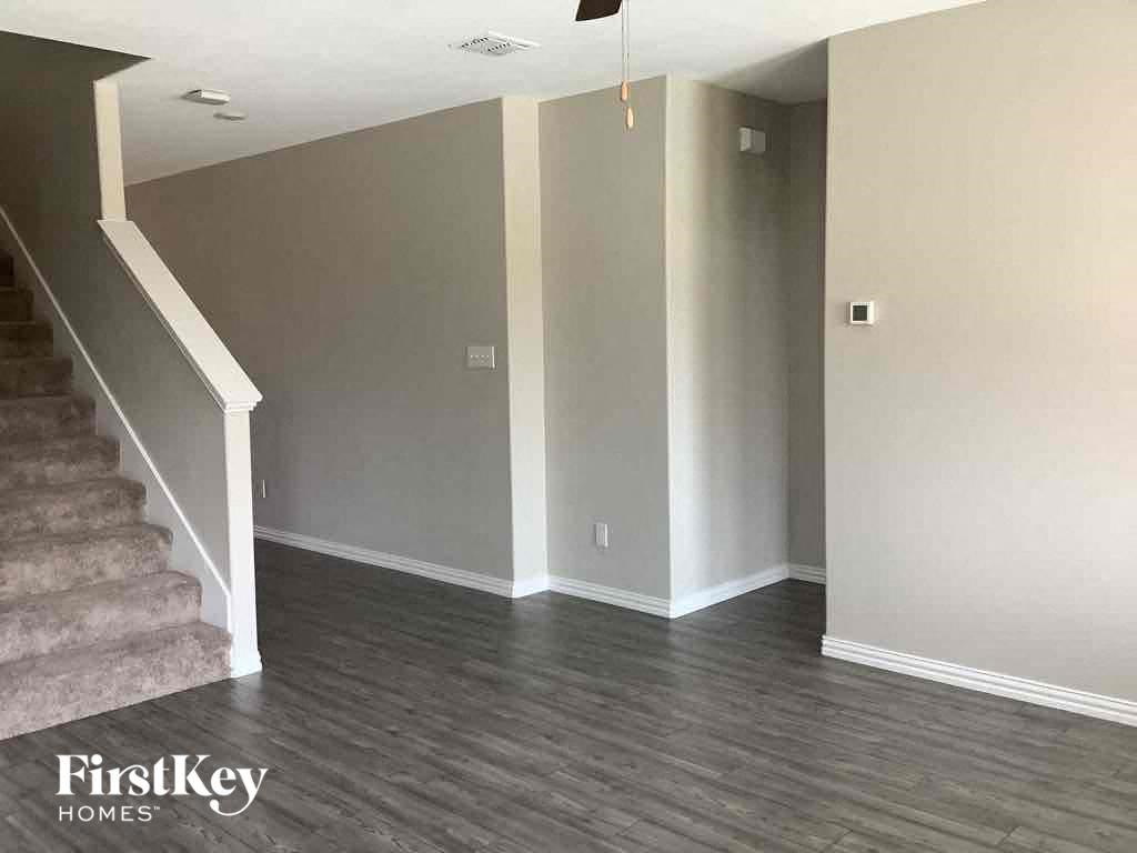 an empty living room with gray walls and a staircase