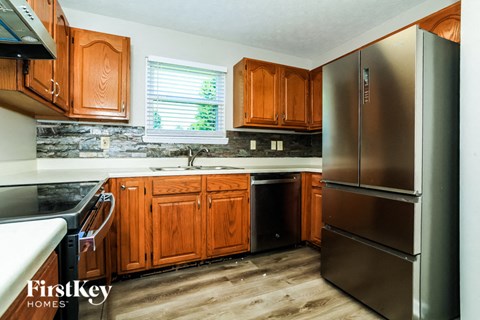 A kitchen with wooden cabinets and a stainless steel refrigerator.