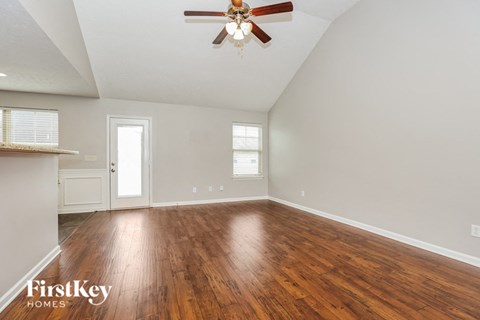 an empty living room with wood floors and a ceiling fan