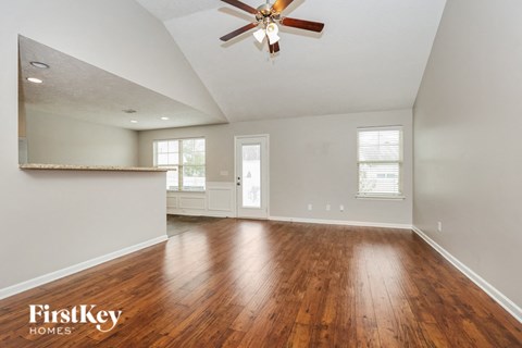 an empty living room with wood floors and a ceiling fan