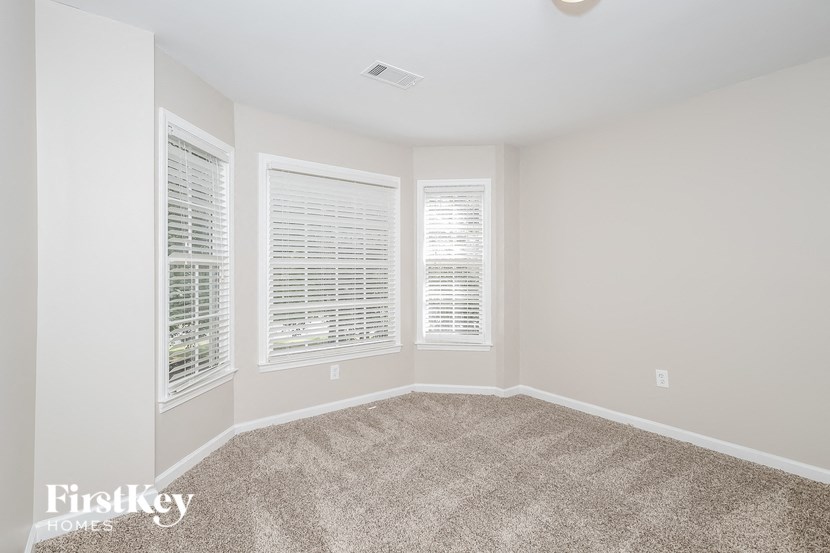 a bedroom with three windows and a carpeted floor