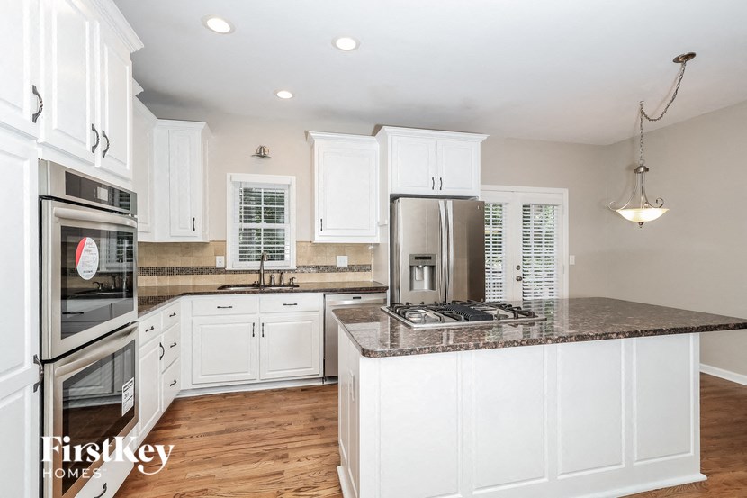 a white kitchen with granite counter tops and white cabinets