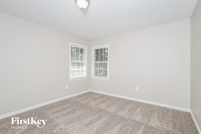 the spacious living room with carpeting and two windows