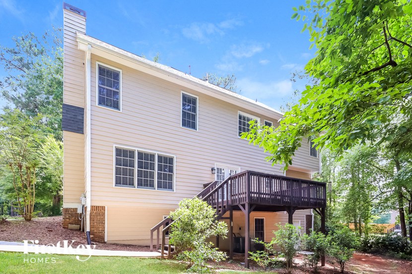 a yellow house with a deck and a tree