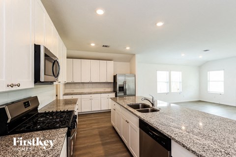 A kitchen with granite countertops and a stove top oven.