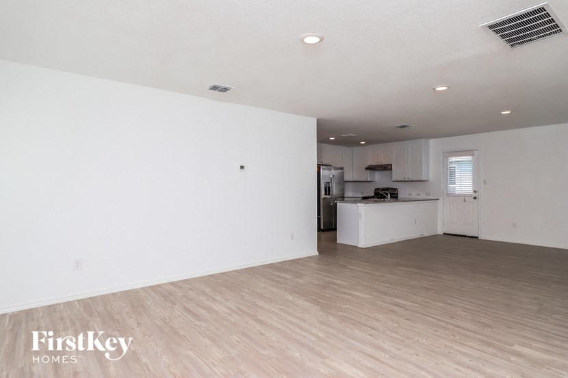 an empty living room and kitchen with white walls and wood floors