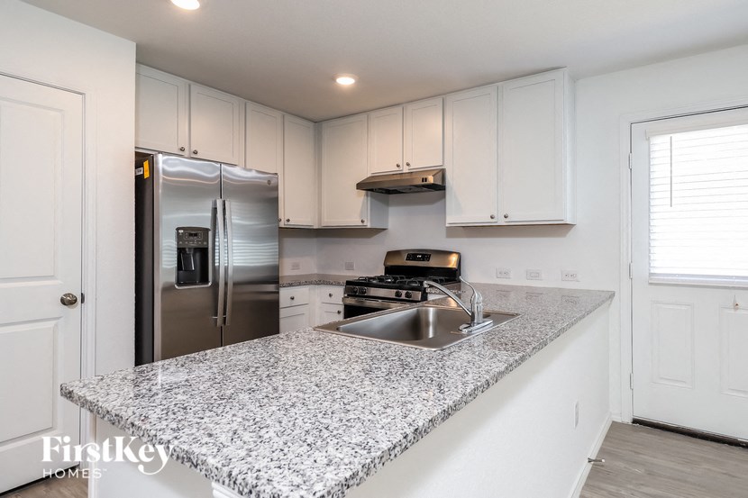 a kitchen with granite counter top and stainless steel refrigerator
