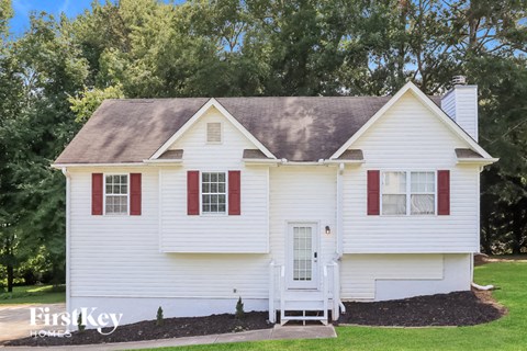 a white house with red shutters and a lawn and trees