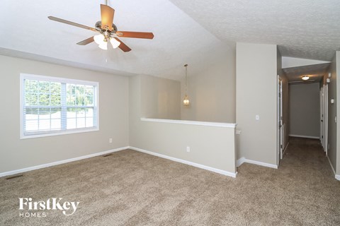 a living room with carpet and a ceiling fan