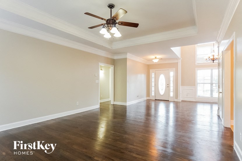 an empty living room with wood floors and a ceiling fan
