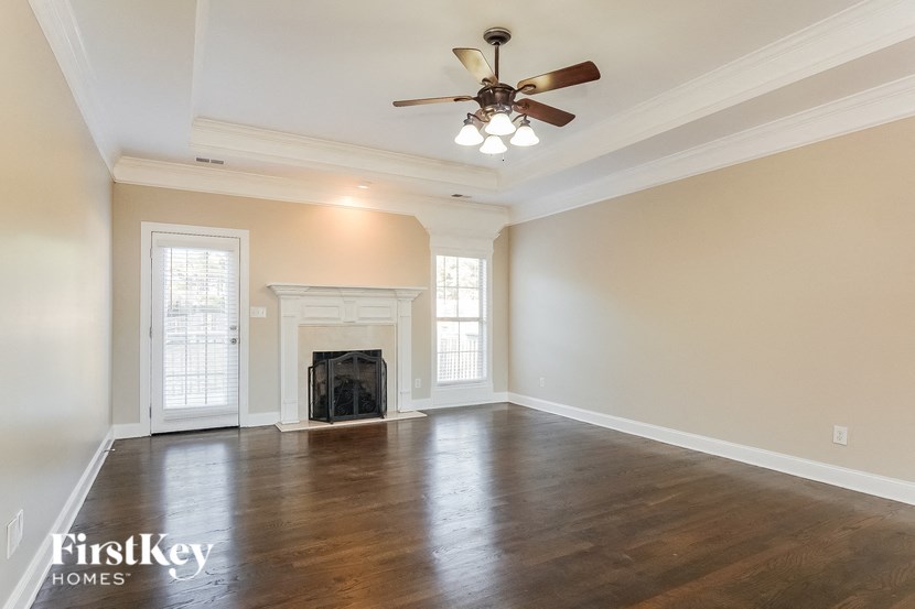 an empty living room with a ceiling fan and a fireplace