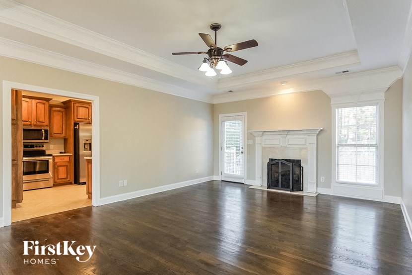 an empty living room with a fireplace and a ceiling fan