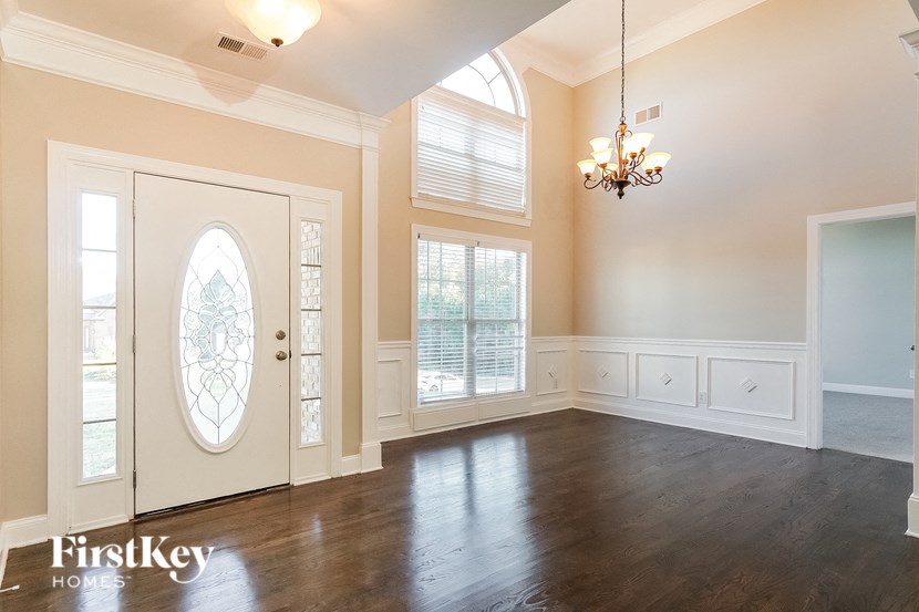 an empty living room with a white door and a window