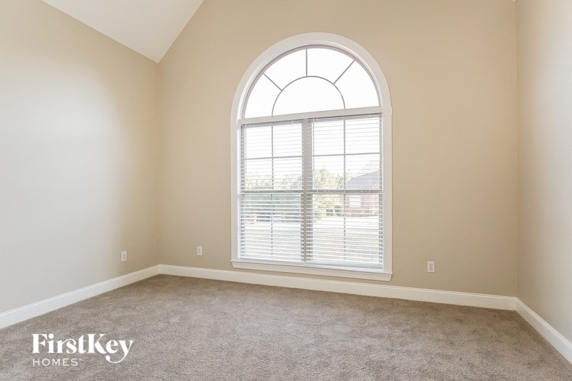 an empty living room with a large arched window