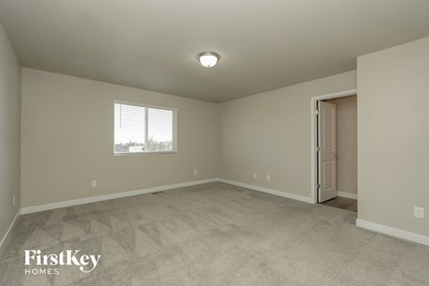 A room with a carpeted floor and a door on the right side.