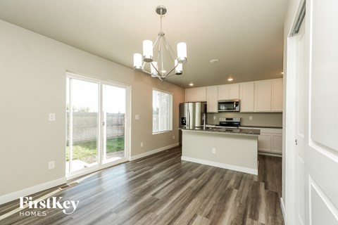 A well-lit kitchen and living room with wooden floors and white walls.