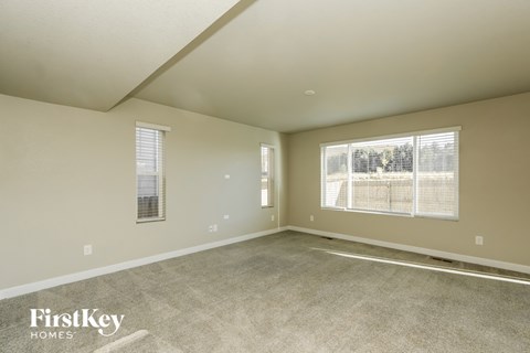 A spacious empty room with a carpeted floor and two windows.
