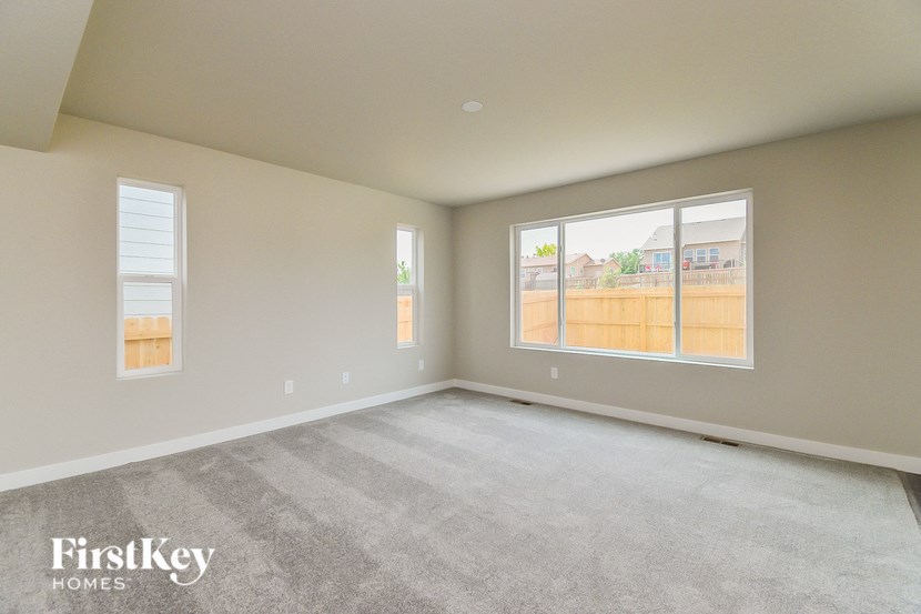 the living room of a new home with carpet and large windows