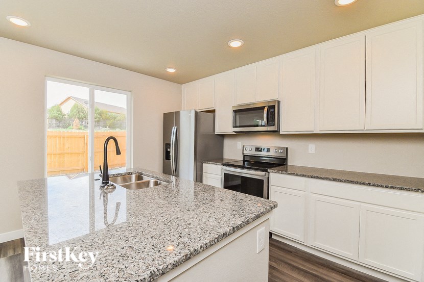 a kitchen with white cabinets and granite counter tops and a sink