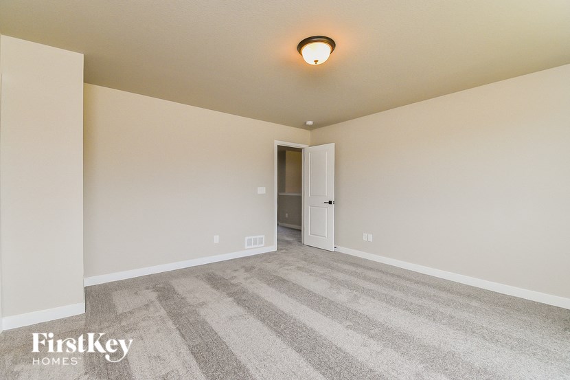 a spacious living room with carpet and a door to the bathroom
