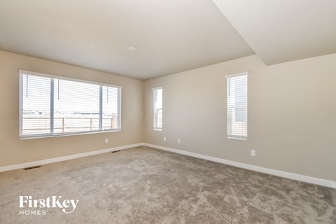 A spacious room with a carpeted floor and two windows.