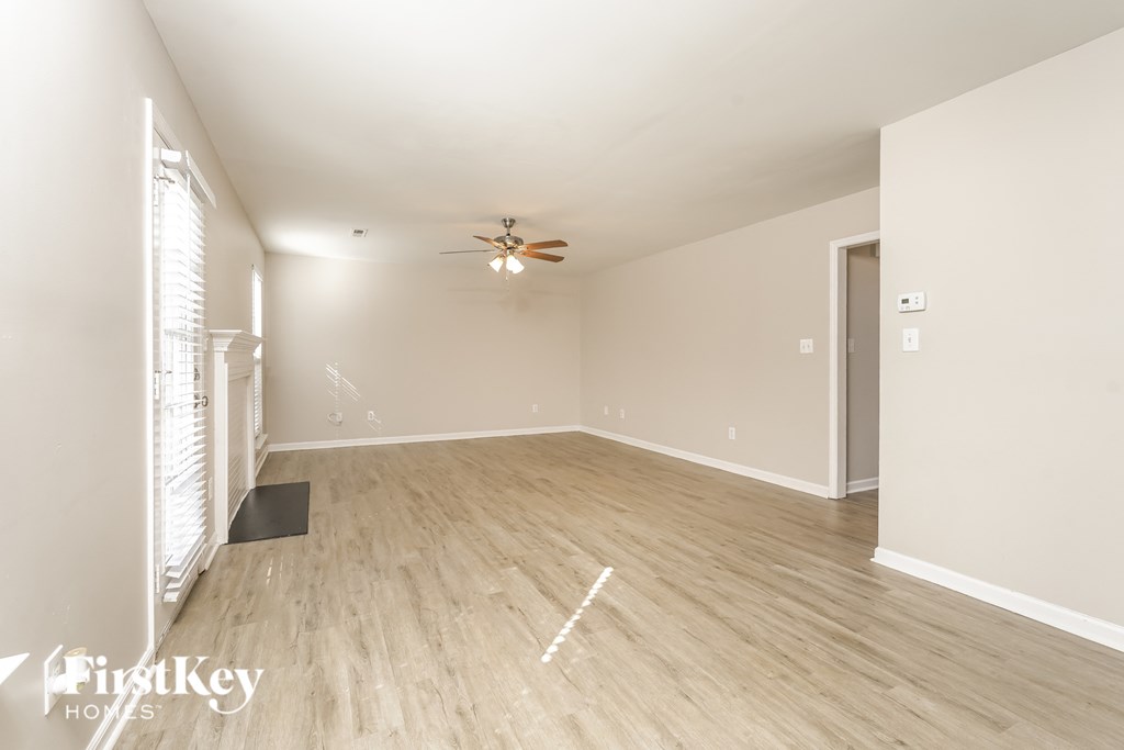a spacious living room with hardwood floors and a ceiling fan