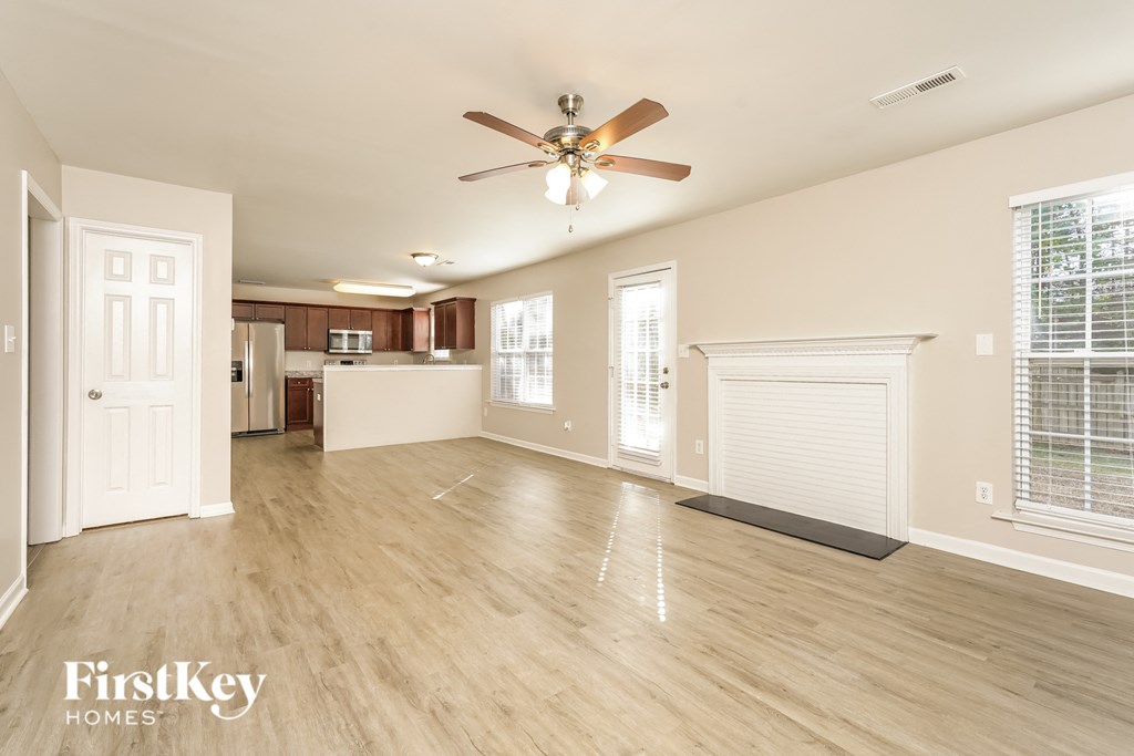 an empty living room with a ceiling fan and a kitchen