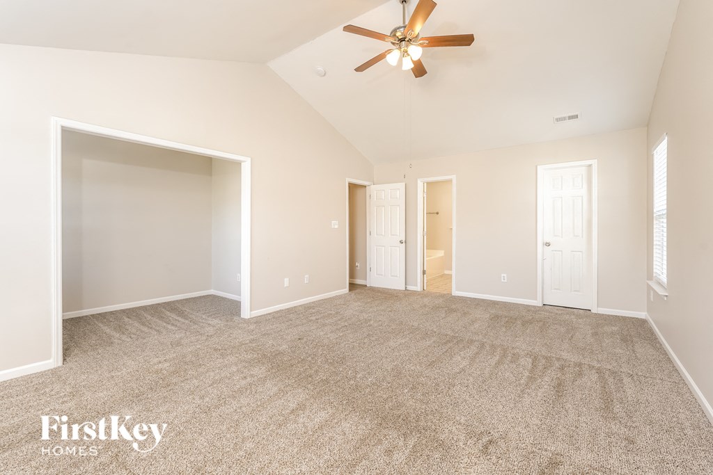 a spacious living room with carpet and a ceiling fan