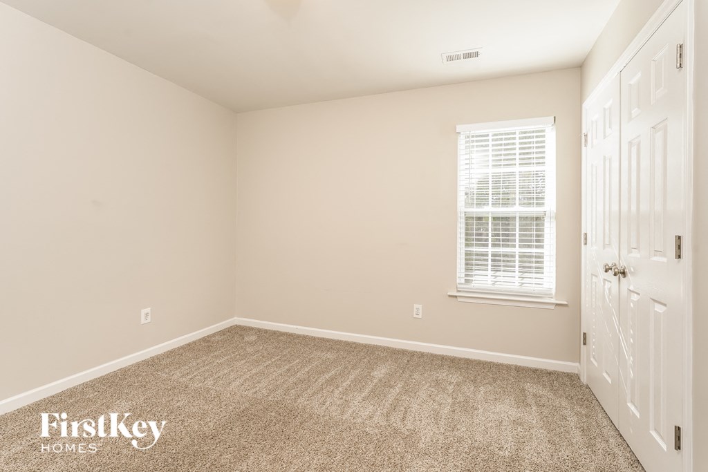 a bedroom with carpet and a window and a white door