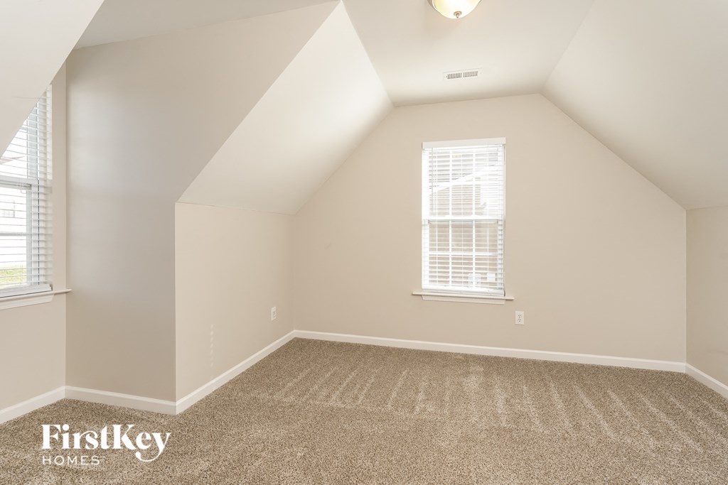 the upstairs loft of a home with a carpeted floor and two windows