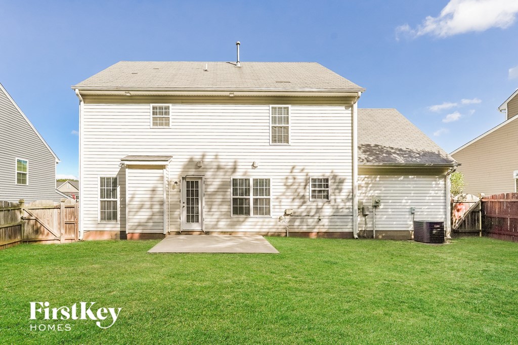 the back of a white house with a yard and a fence