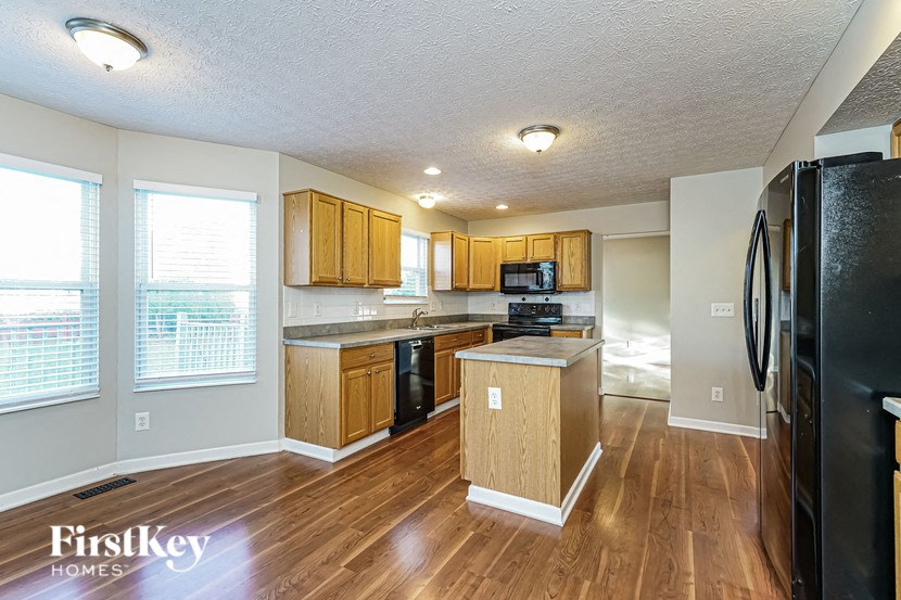 a kitchen with wood flooring and a black refrigerator