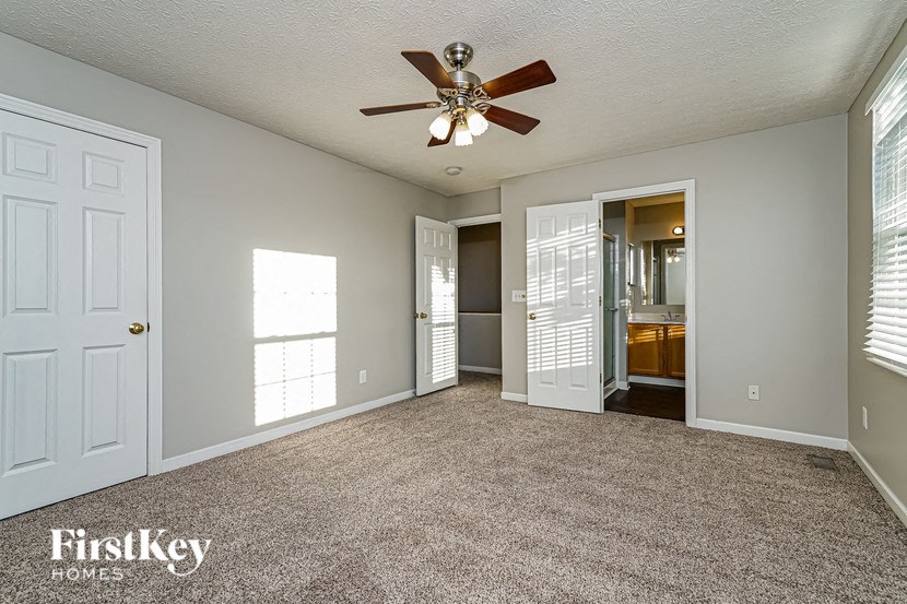 a living room with a ceiling fan and a door to a bathroom