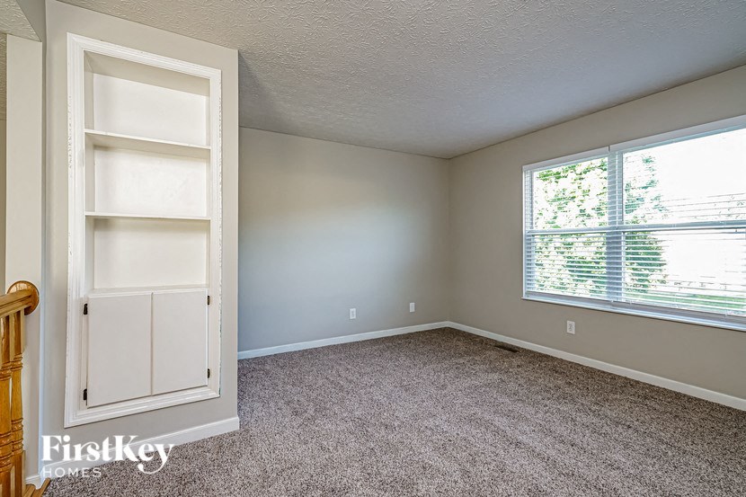 a bedroom with a large window and a white book shelf