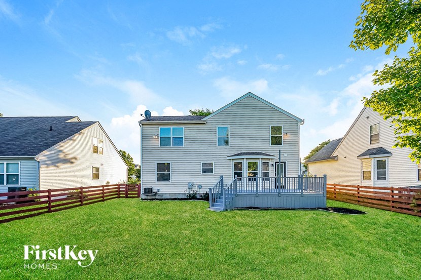 a backyard with a white house and a fence