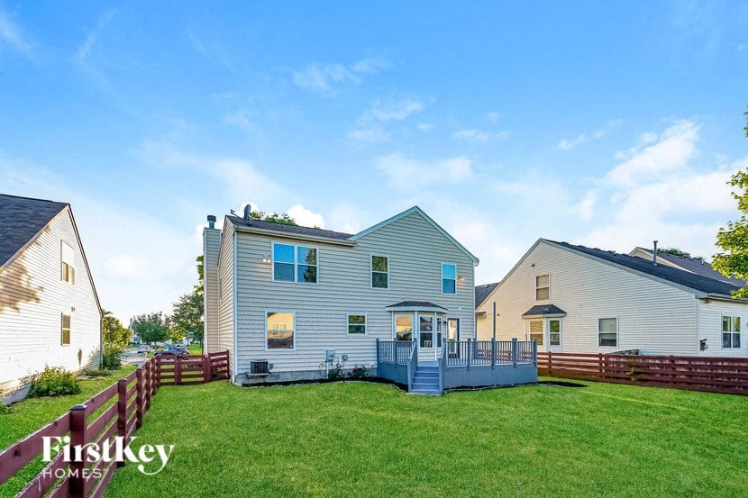 a white house with a deck on a green lawn