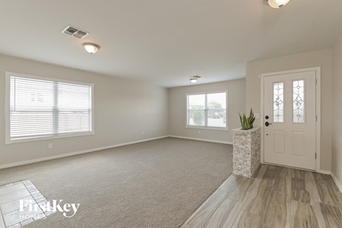 A well-lit, empty room with a door, windows, and a carpeted floor.