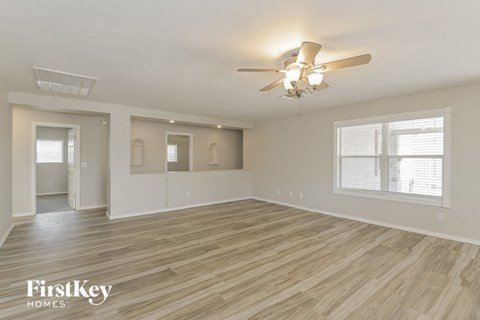A spacious room with wooden flooring and a ceiling fan.