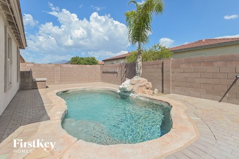 A small pool with a waterfall and a palm tree in the background.