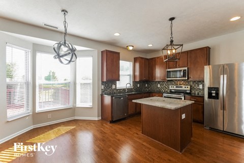 A kitchen with wooden cabinets and a stainless steel refrigerator.