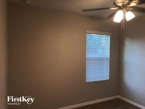 an empty room with a ceiling fan and a window