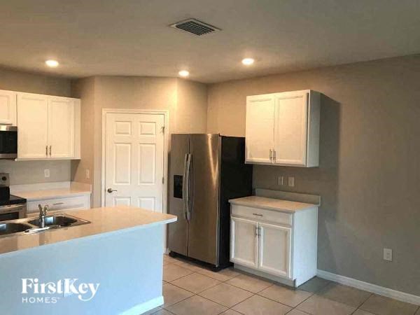 a kitchen with white cabinets and a stainless steel refrigerator