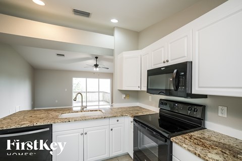 A kitchen with a black stove top oven and a black microwave above it.
