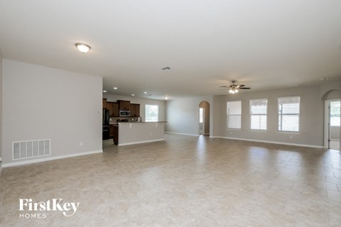 A spacious empty room with a ceiling fan and a radiator on the wall.