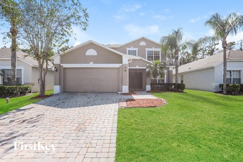 a beige house with a driveway and palm trees