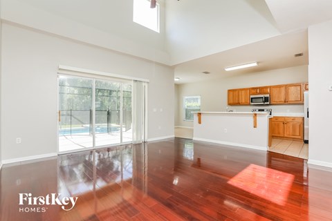 an empty living room and kitchen with wood flooring and a pool