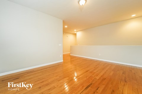 the living room and dining room of a house with wood floors and white walls