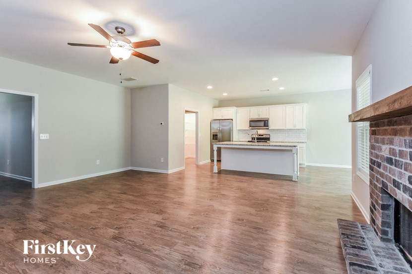 an empty living room with a fireplace and a kitchen